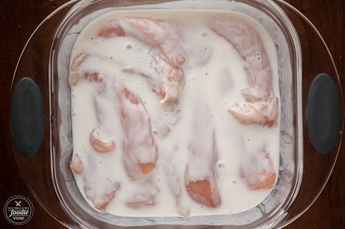 chicken tenders soaking in pan of buttermilk