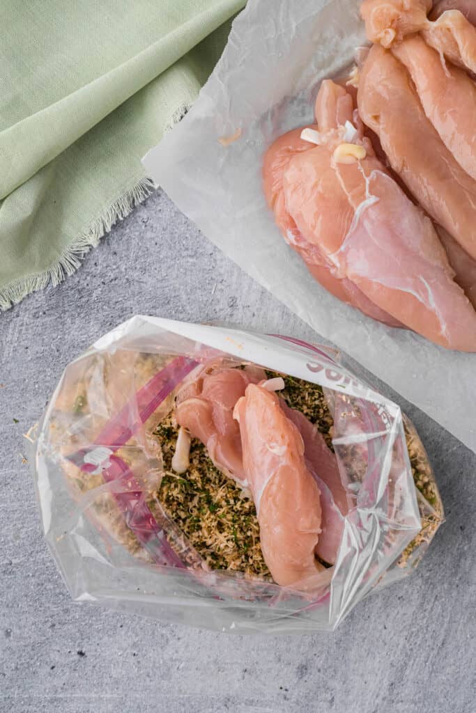 coating chicken breasts with bread crumbs and herbs.