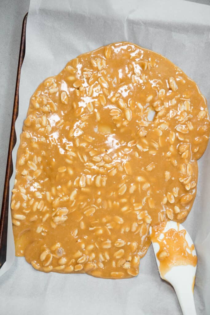 homemade peanut brittle that has been poured onto parchment paper
