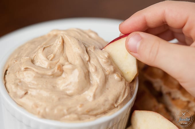 dipping apple into fruit dip made with peanut butter