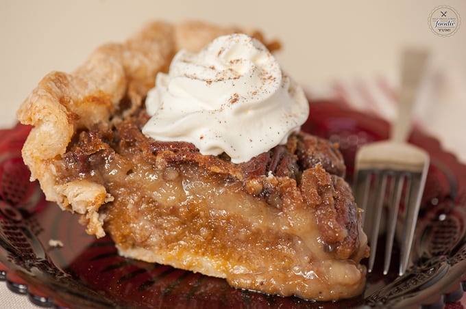 A close up of a piece of pie, with pecans and pumpkin