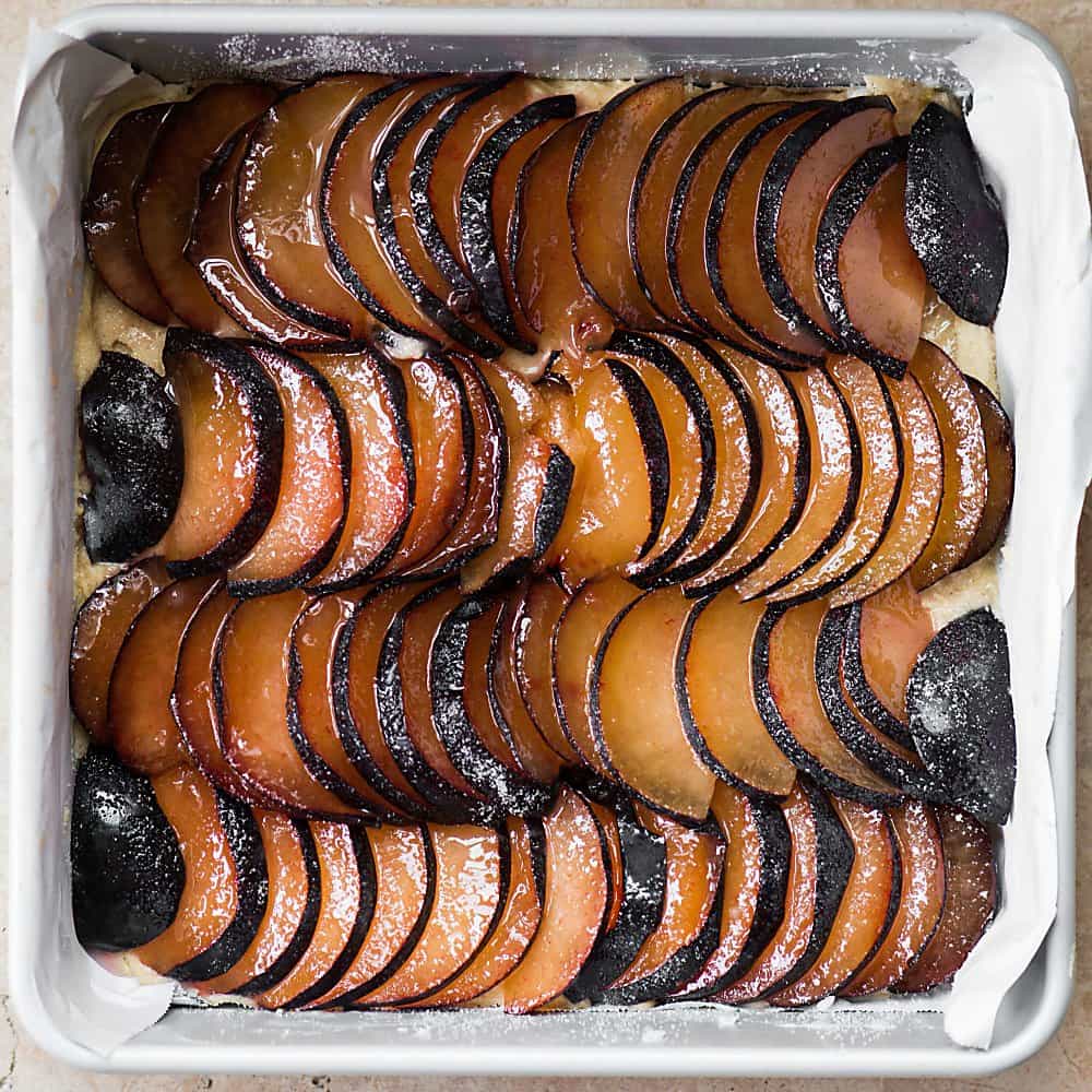cake topped with fresh plums before it is baked