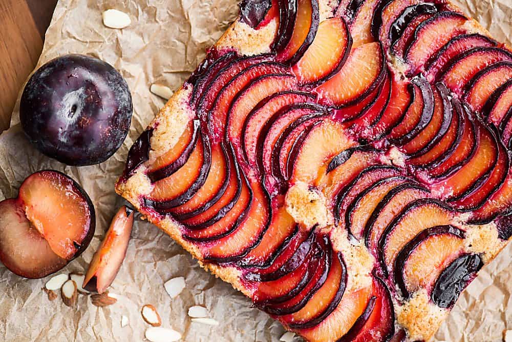 cake topped with fresh plum and almonds