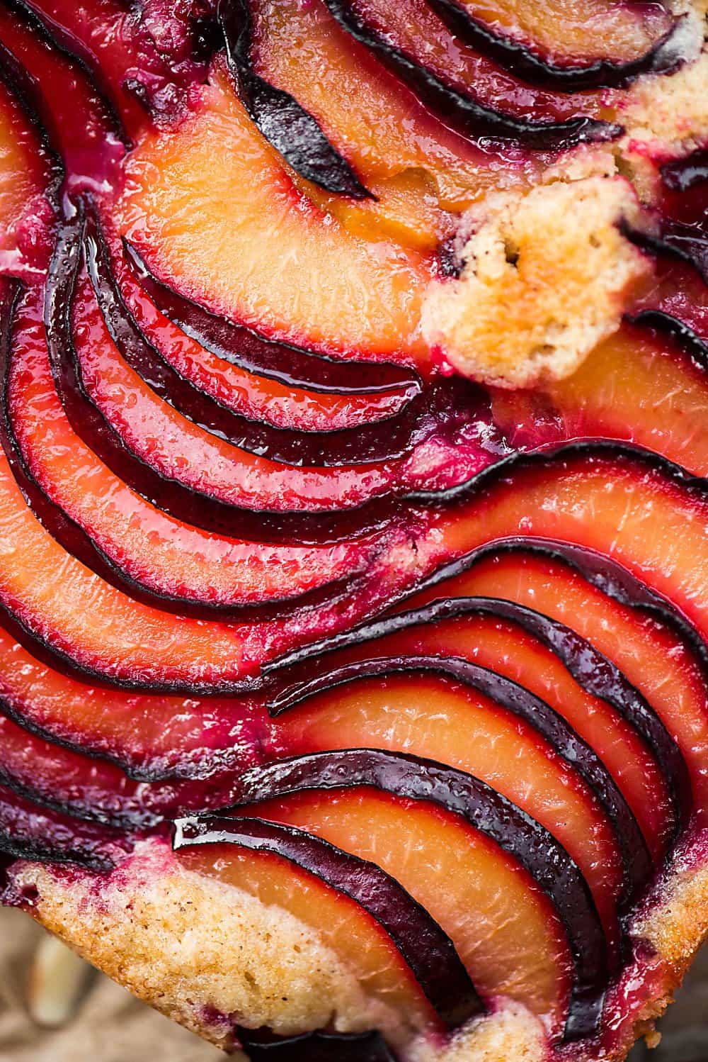 A close up of sliced plums on cake