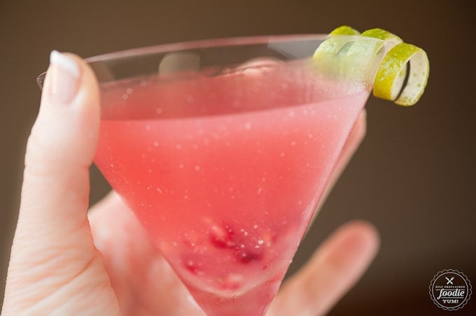 a hand holding a glass of pomegranate Cosmopolitan 