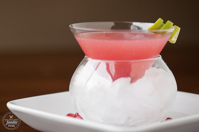 a close up of a Pomegranate Cosmopolitan with lime garnish