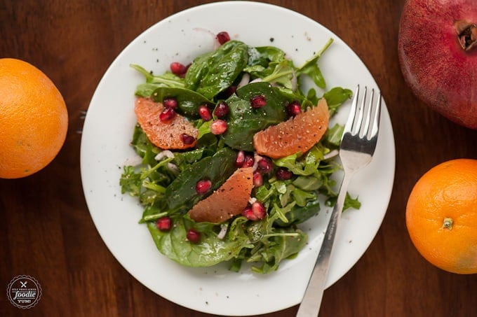 lightly dressed arugula and spinach with orange segments and pomegranate