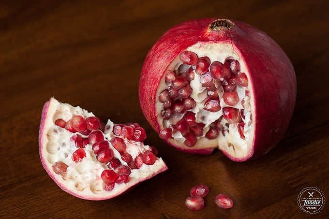 a fresh pomegranate with a piece cut out on wood table