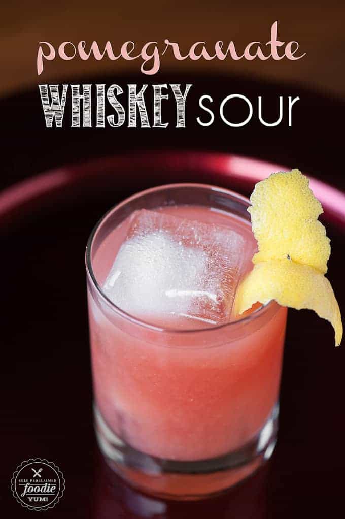 A glass of pomegranate Whiskey sour with lemon garnish
