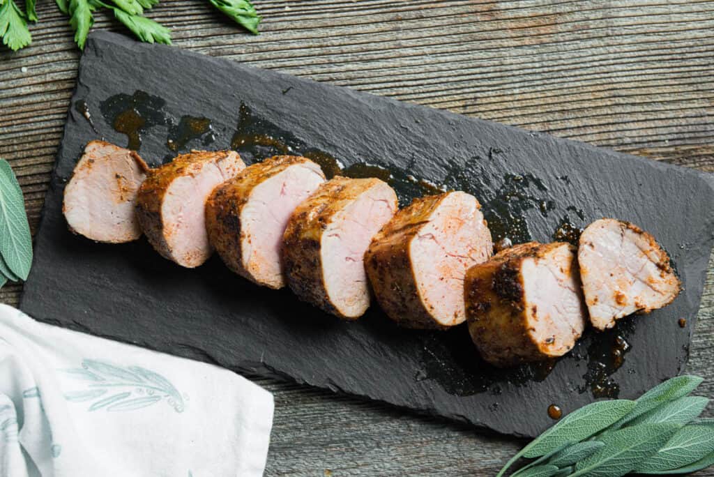 sliced pork tenderloin on black platter
