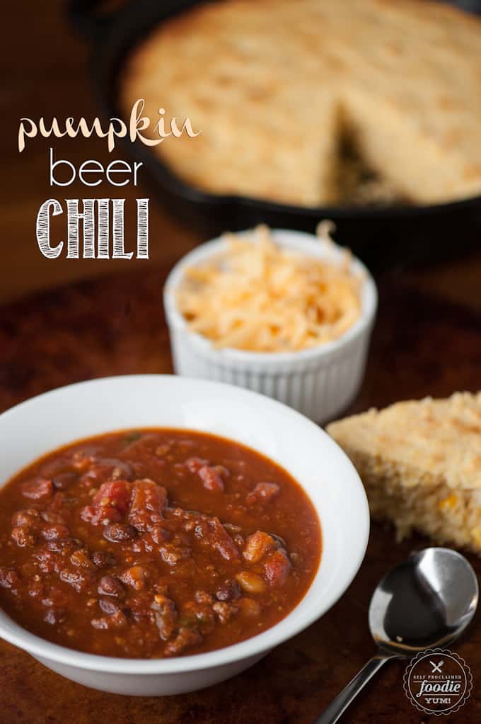 pumpkin beer chili with cheese and cornbread in the background