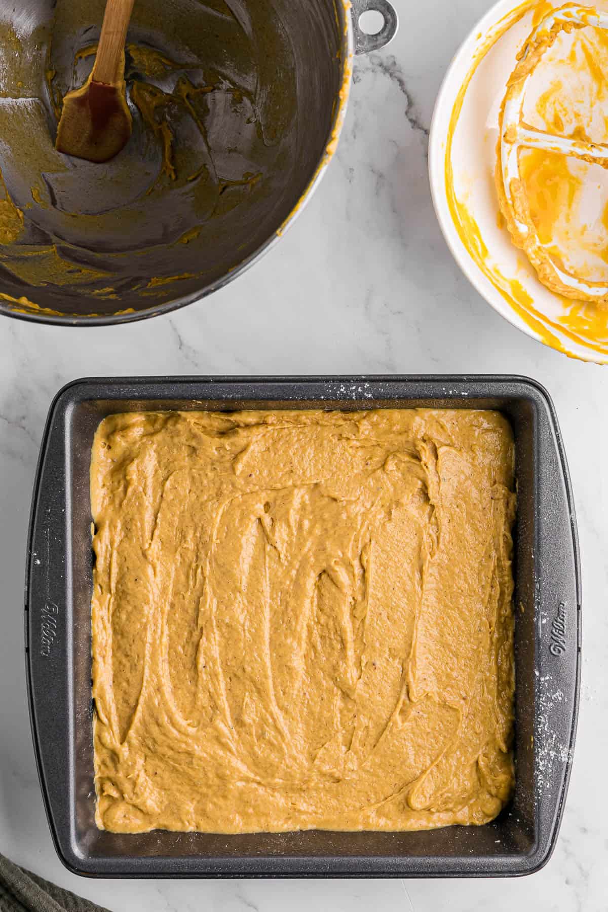spreading pumpkin coffee cake batter in square baking pan.