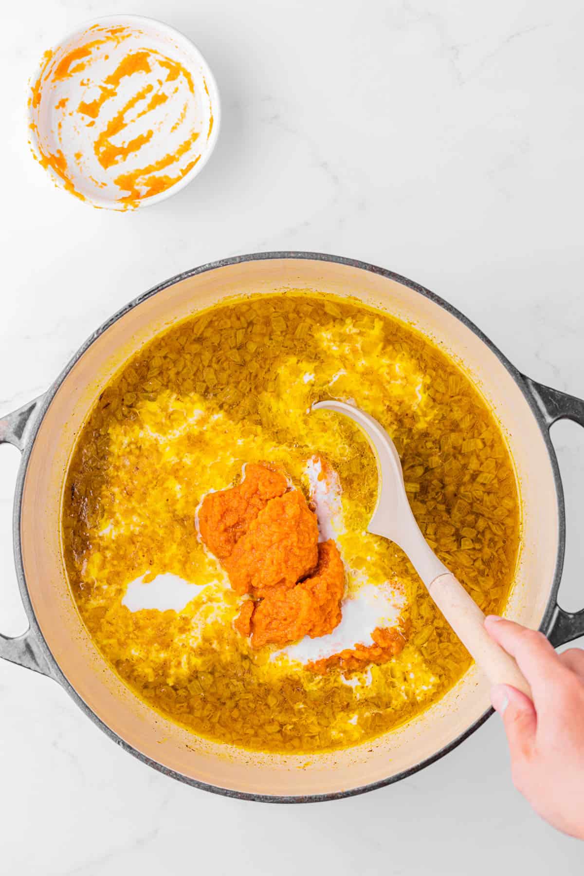 Adding pureed pumpkin and coconut milk to soup base.