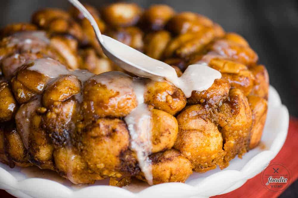 spoon of cinnamon glaze on homemade pumpkin spice monkey bread