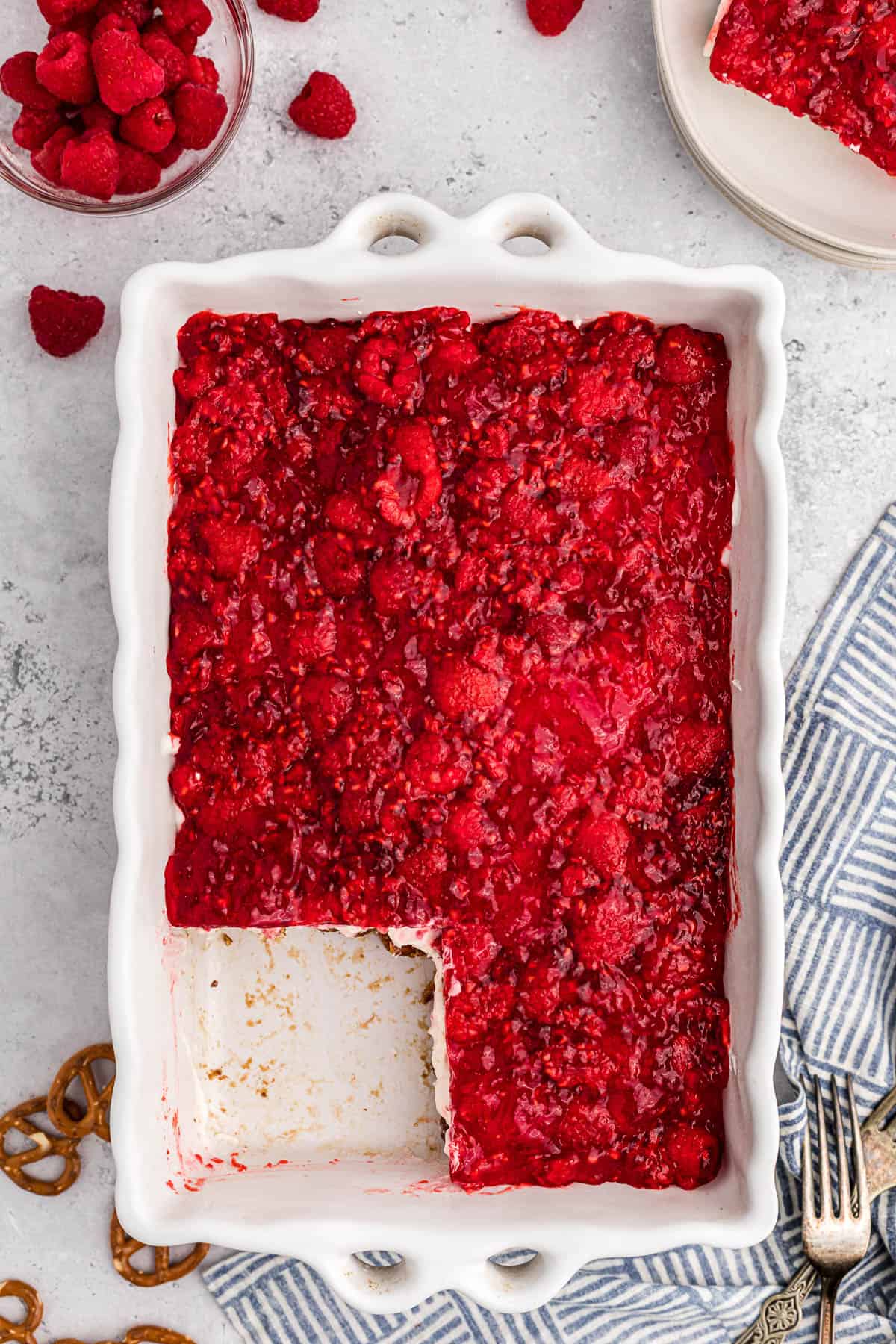 casserole dish with raspberry pretzel salad with piece taken out.