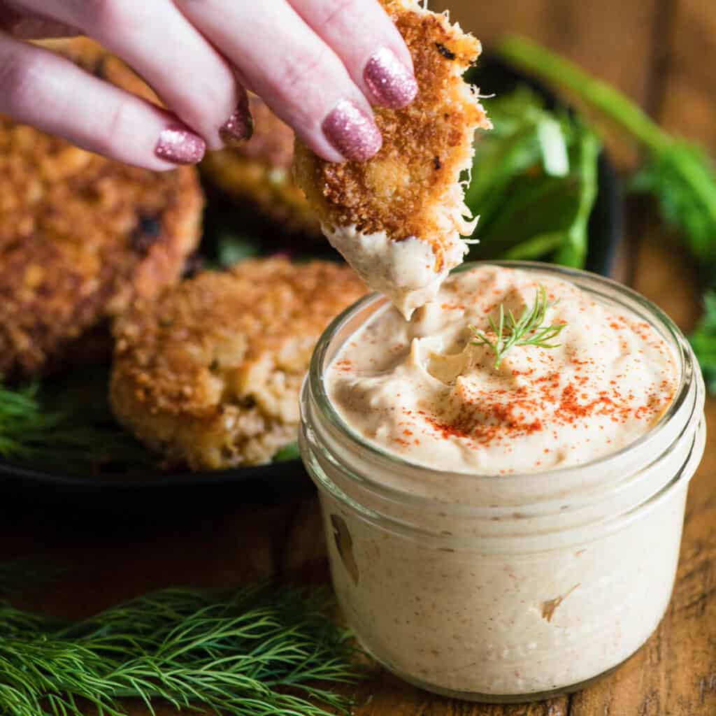 Dipping a homemade crab cake into a mason jar of remoulade sauce.