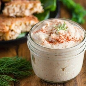 mason jar of homemade remoulade sauce with crab cakes in the background.