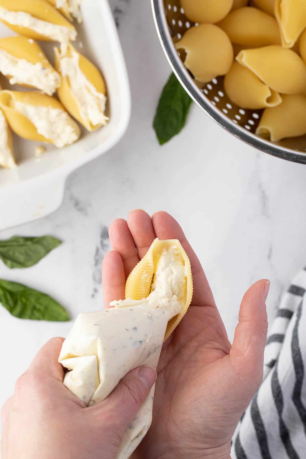 filling pasta shells with cheese mixture using piping bag