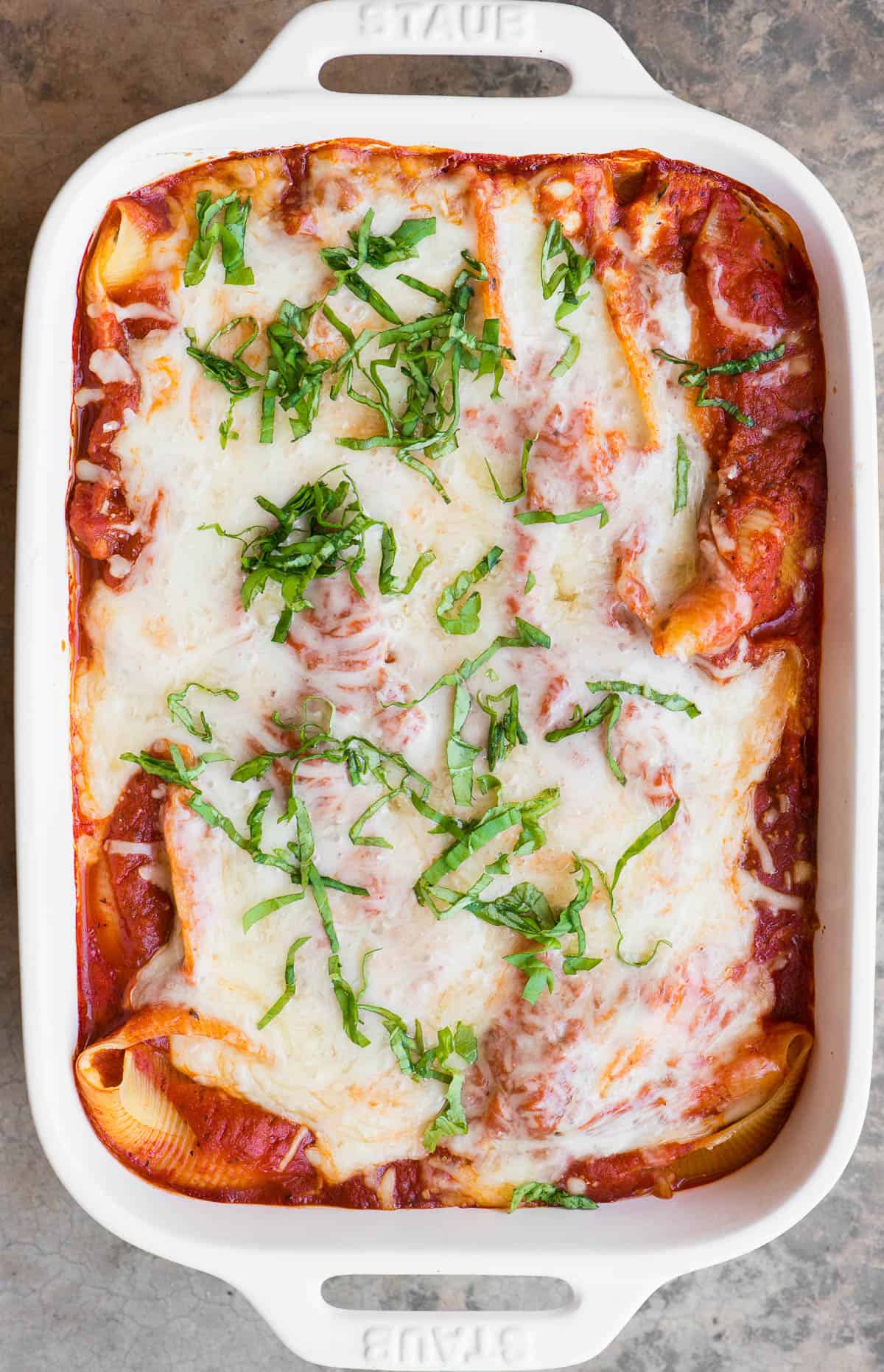 top view casserole dish of stuffed shells topped with cheese and sauce