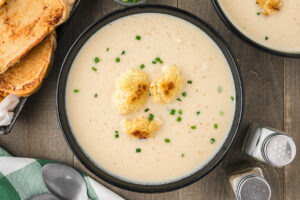 bowl of roasted cauliflower soup with pieces of roasted cauliflower on top.