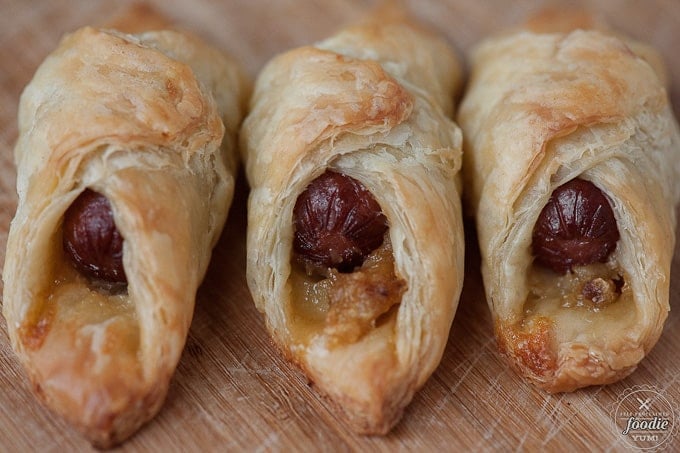 a close up of mini hot dogs wrapped win puff pastry with roasted garlic