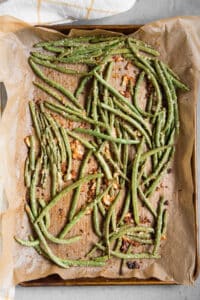 roasted green beans with parmesan and garlic on parchment paper.