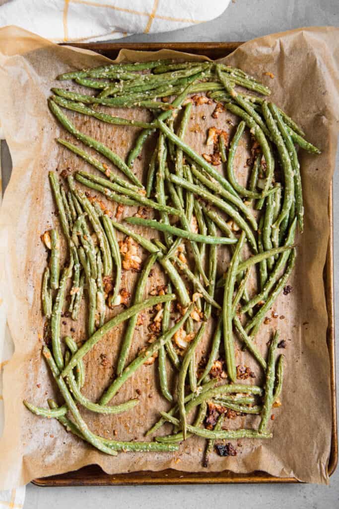 roasted green beans with garlic on baking sheet.