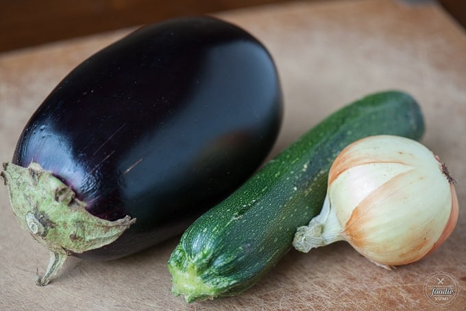eggplant, zucchini, onion on brown cutting board