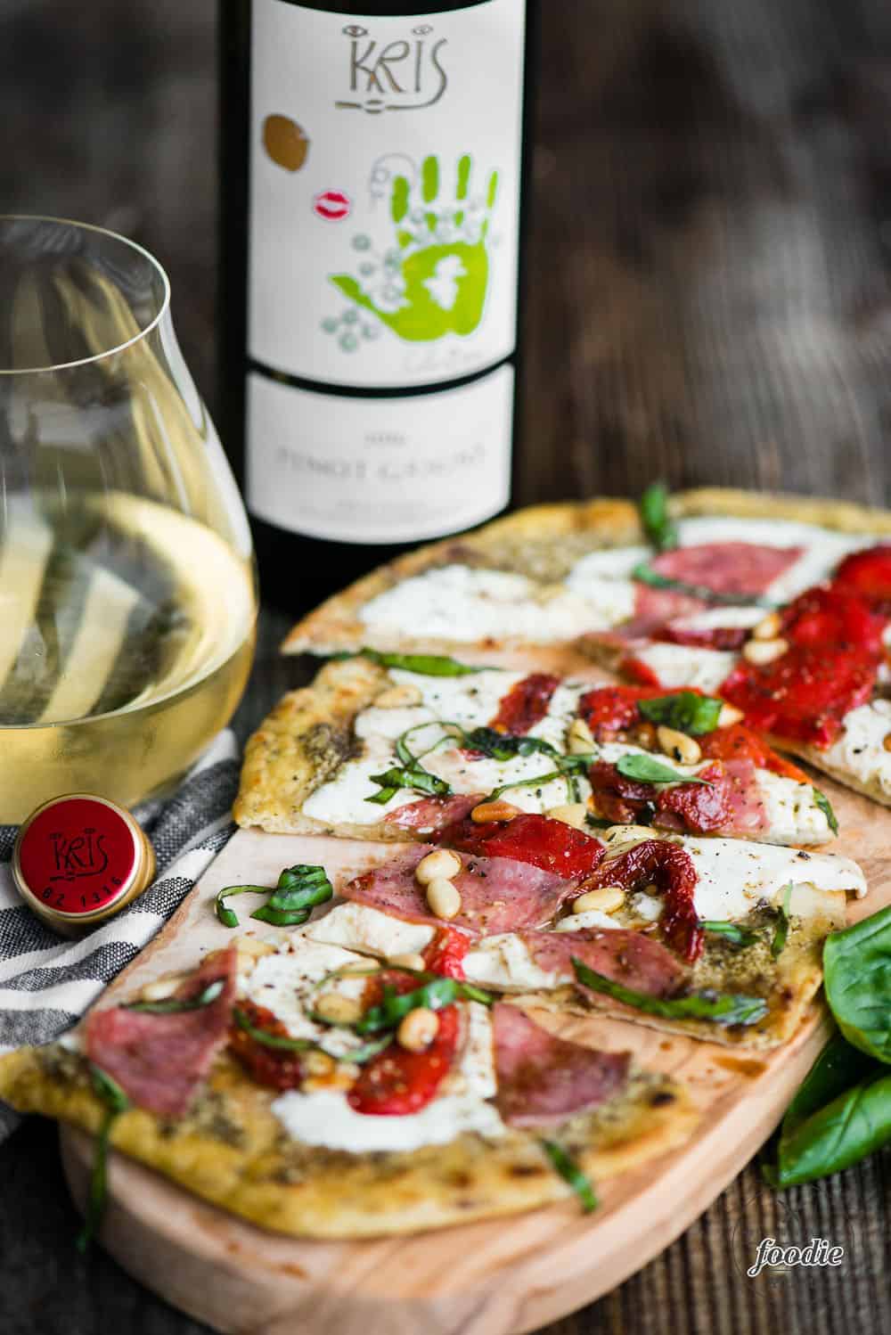 rustic homemade flatbread pizza with a glass of pinot grigio