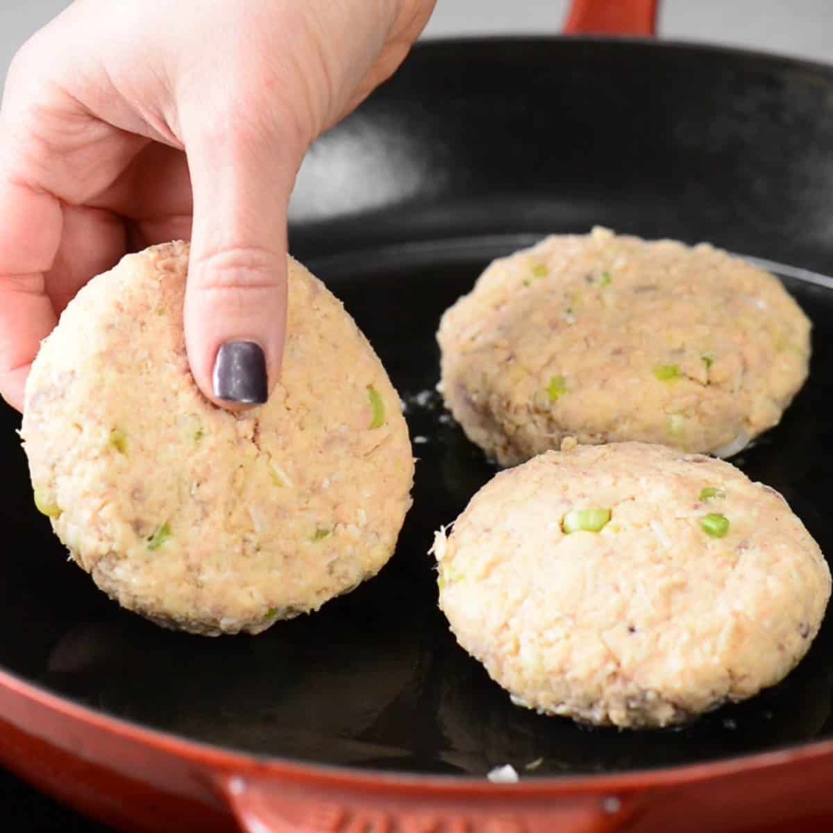 placing uncooked salmon patties in hot pan