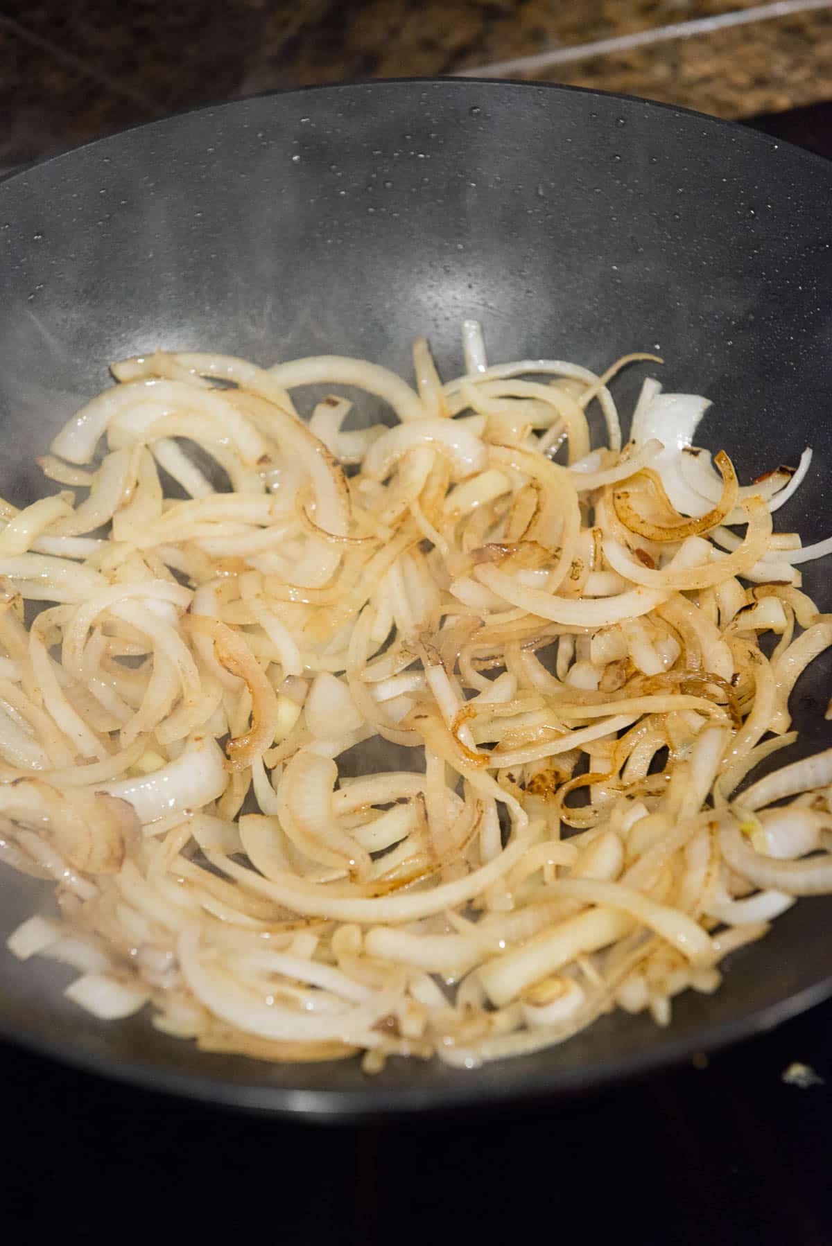 browning onion slices in wok pan