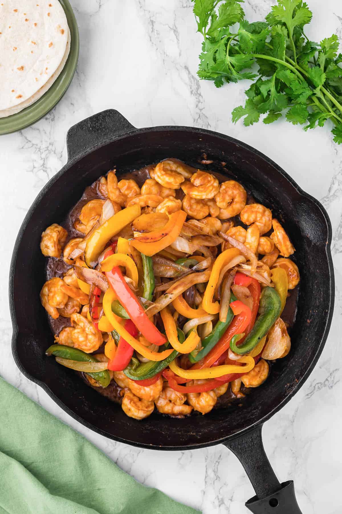 combining peppers and onions with shrimp for fajita recipe.