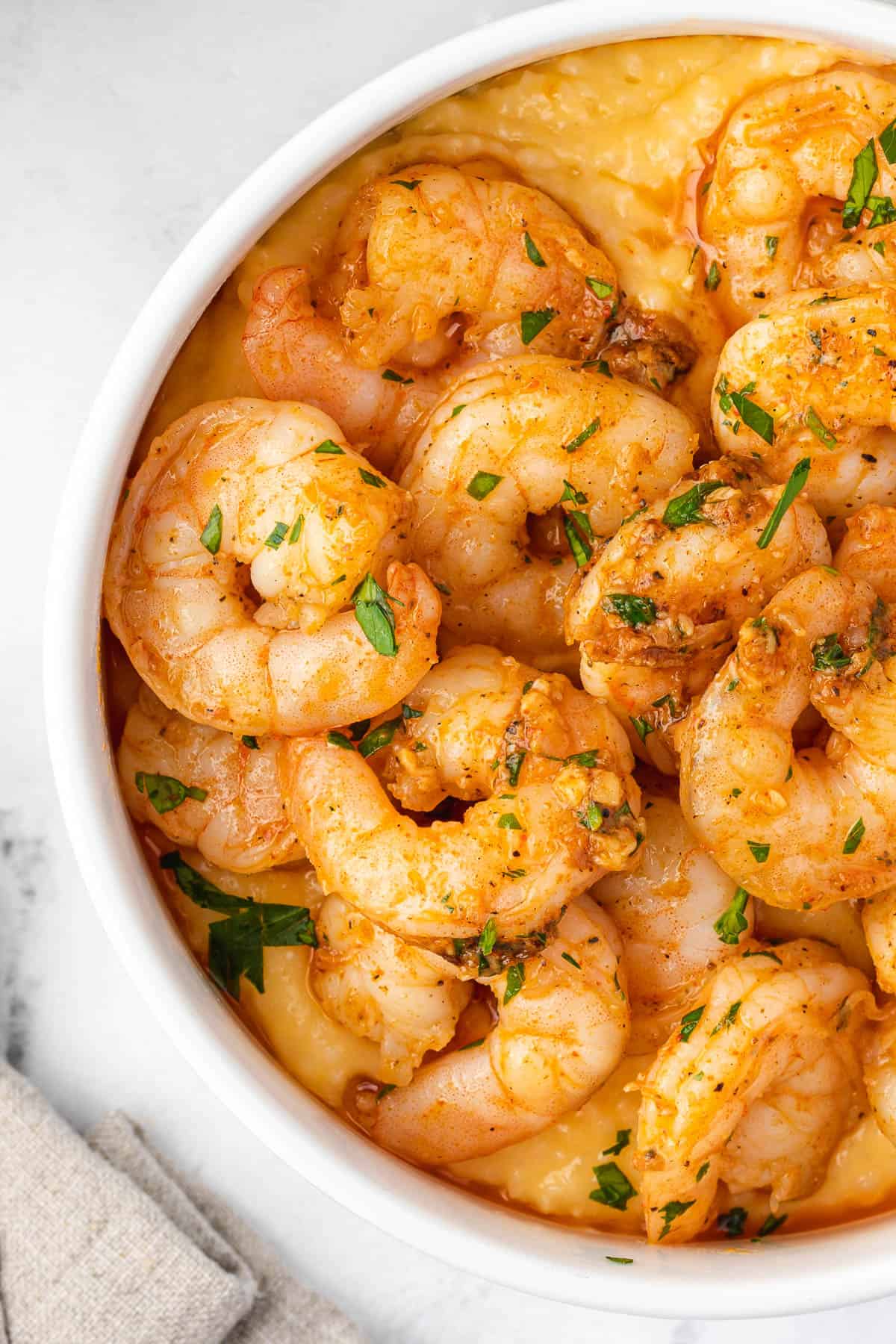close-up of seared shrimp in a red pan sauce over cheese grits
