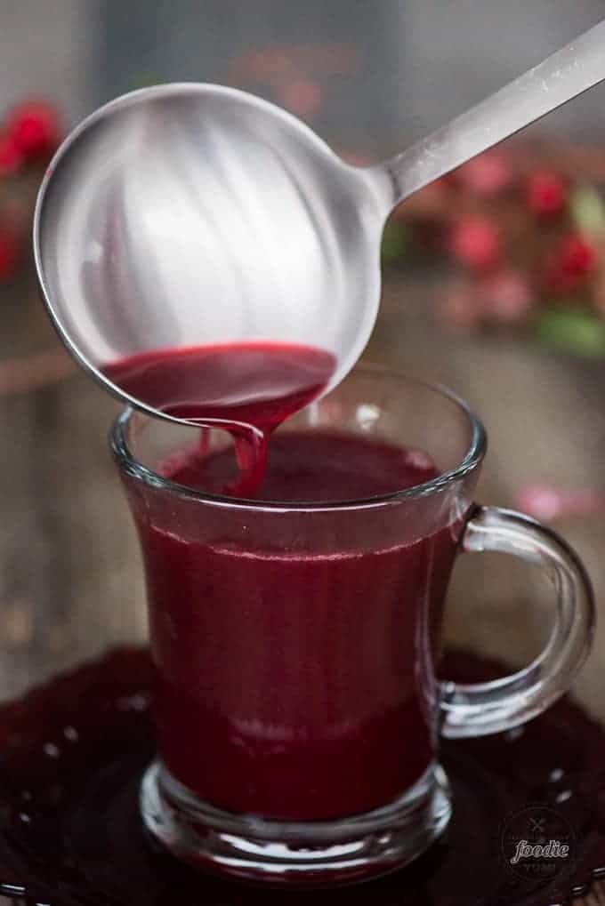 Party punch from frozen berries and spiced cider from ladle to glass