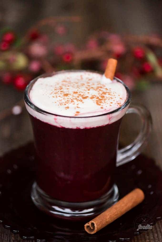 warm berry cider with whipped cream and a cinnamon stick