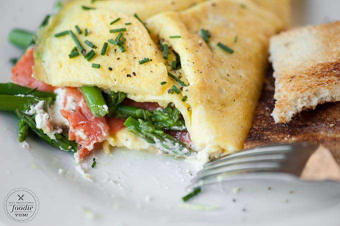 A close up of an omelet with asparagus, goat cheese, and smoked salmon