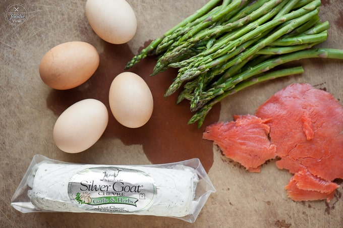 eggs, asparagus, smoked salmon, and goat cheese on brown cutting board