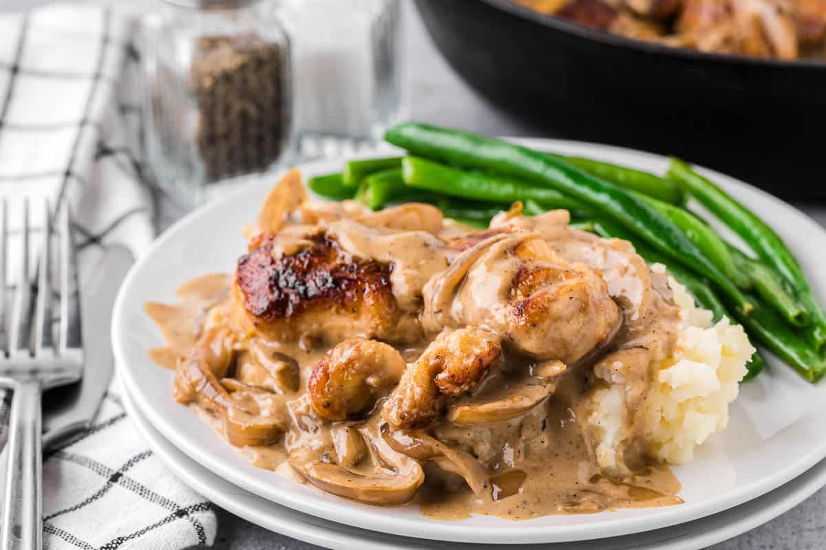 smothered chicken breasts in creamy onion gravy over mashed potatoes with green beans.