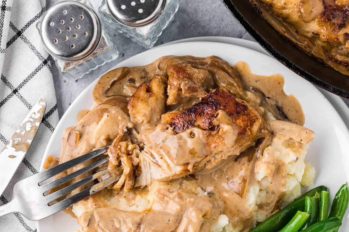 cutting into chicken breast with onion gravy.