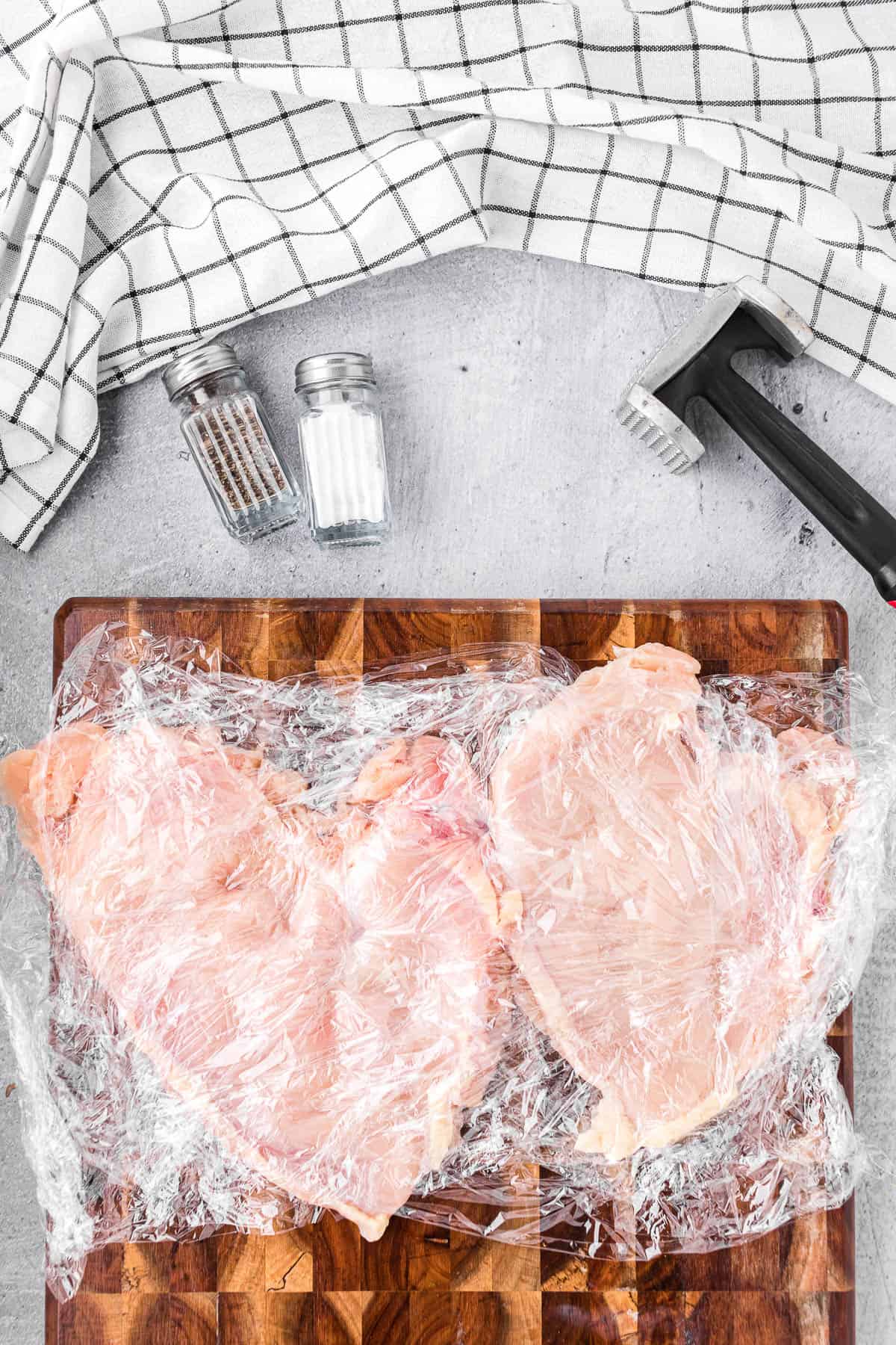 pounding chicken breasts flat in between plastic wrap.