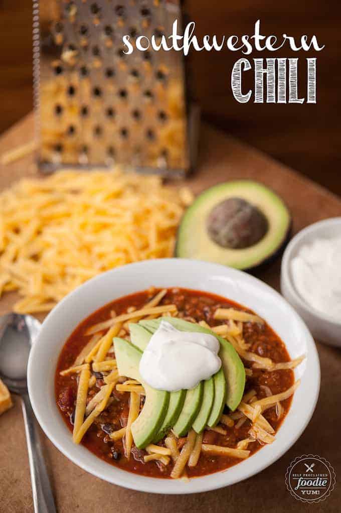 bowl of chili with avocado, cheese and sour cream
