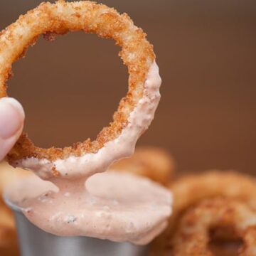 dipping an onion ring into homemade fry sauce
