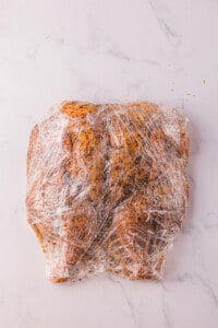 spatchcock smoked chicken with dry rub wrapped tightly in plastic wrap