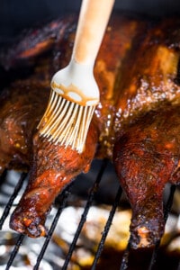 brushing bbq sauce on spatchcock smoked chicken