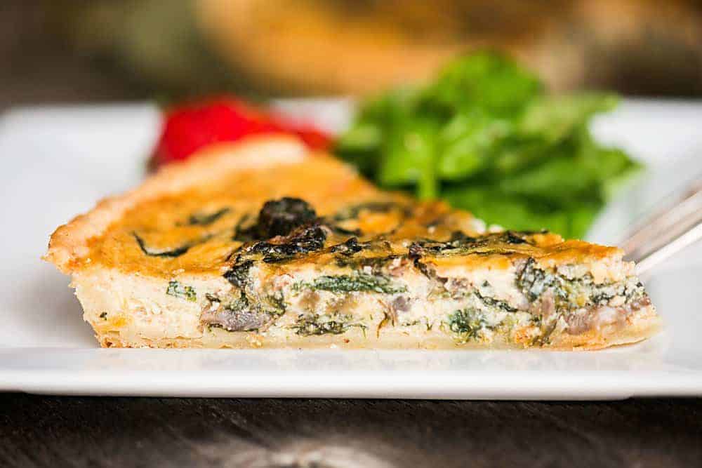 slice of spinach quiche with mushrooms.