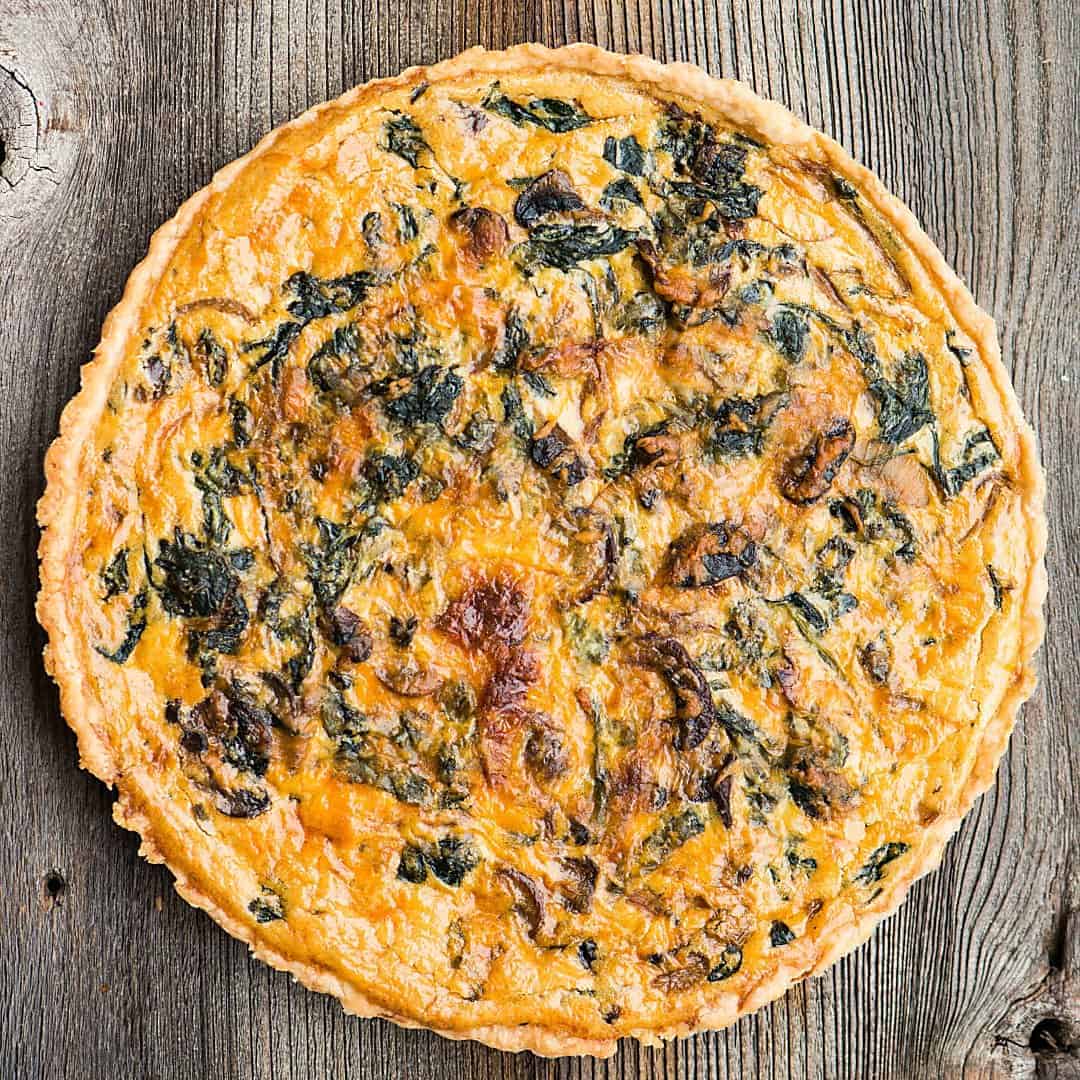 top of a whole quiche with spinach and mushrooms