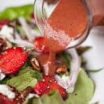 strawberry basil vinaigrette being poured on a salad
