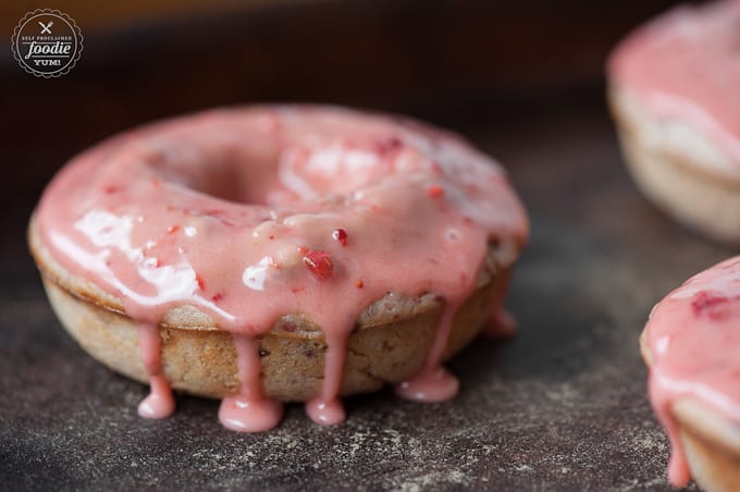 A close up of a doughnut with warm strawberry glaze