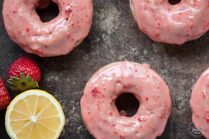 Looking down at pink strawberry baked donuts with lemon
