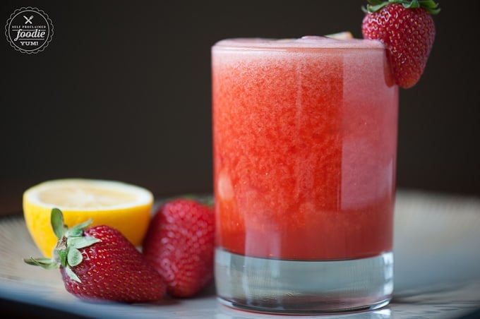 A close up of a glass of whiskey with Strawberry and Lemonade